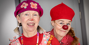 Sjukhusclowner i färgglada kläder och röda näsor