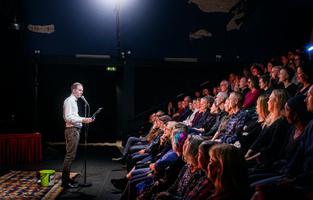 På bild: Michael Horvath Dahlman. Klubb Bubbla på Nya China. 8 novmber 2022. Poesi kan vara brevet du skrev men aldrig skickade till din hemliga kärlek i skolan, eller ett språkmaterialistiskt experiment om E-nummer i mat. Det kan vara kopierat i smyg på jobbet eller tryckt i böcker av landets största förlag. Det kan vara skrivet av en professor, eller uppdiktat av en tvååring som sitter uttråkad i en kundvagn och leker med förbipasserande ord. Det kan huggas i sten eller ropas ut över ett torg och försvinna.Klubb Bubbla ställer allt detta på samma scen, och ställer inte det ena ovanför det andra. Därför är det estradpoesins vardagsrum. Här ser du vinnare från Poetry Slam-SM, debutanter från bokförlagen, och kanske någon från ditt kvarter