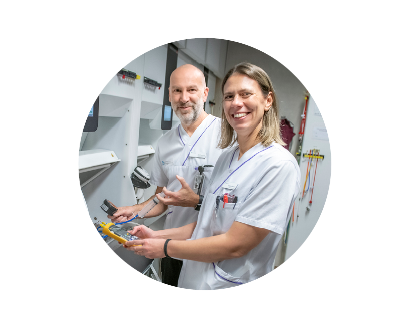 Bild på Aikaterini och Bert som står vid medicinteknisk utrustning